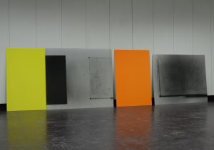 Display of four visual works by Mary Maclean leaning against a wall. Titled "Extremely" by Mary Maclean